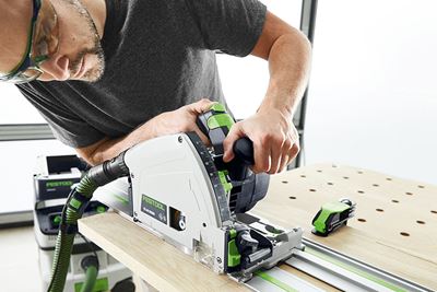 Un hombre corta una tabla con una sierra circular de Festool sobre una mesa multifuncional