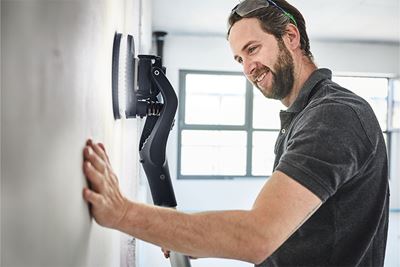 Profesional lija una pared con la lijadora de pared Planex con iluminación
