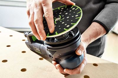 Un profesional coloca el plato lijador en una lijadora Festool