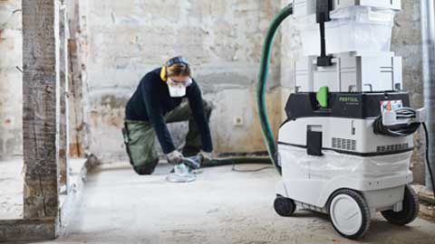 Un profesional está lijando un suelo y utiliza el sistema de lijado de suelos Festool con aspiración.