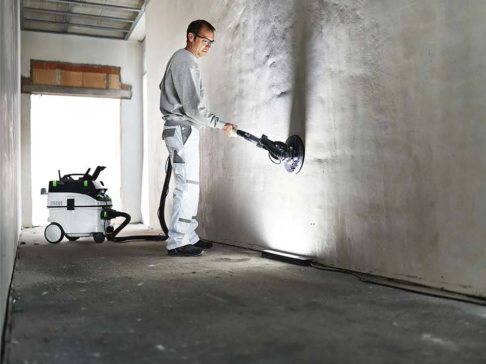 Un artesano ilumina una pared con ayuda del Foco de luz rasante y la lija